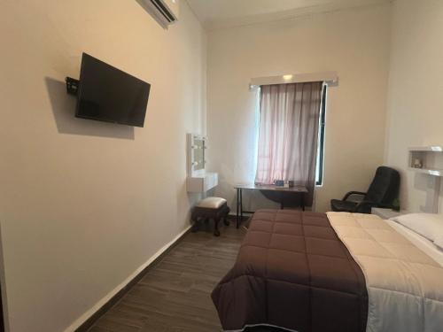 a hotel room with a bed and a flat screen tv at Alameda Suites & CAS - Centro Monterrey in Monterrey