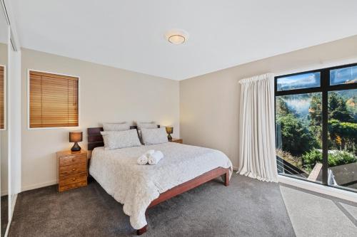 Un dormitorio con una cama y una ventana grande. en Hanmer Haven, en Hanmer Springs