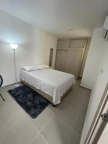 a white bedroom with a bed and a lamp at Apartamento NIZA in Valledupar