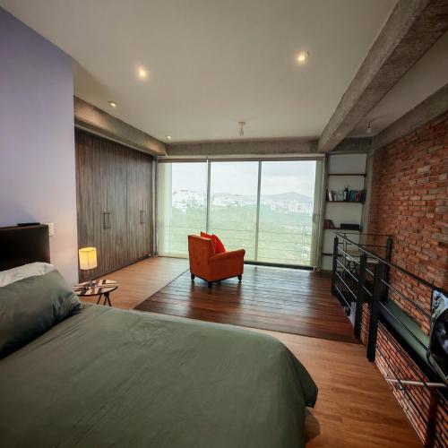 a bedroom with a bed and a chair and a brick wall at Brick Box Loft con Balcon in Hércules