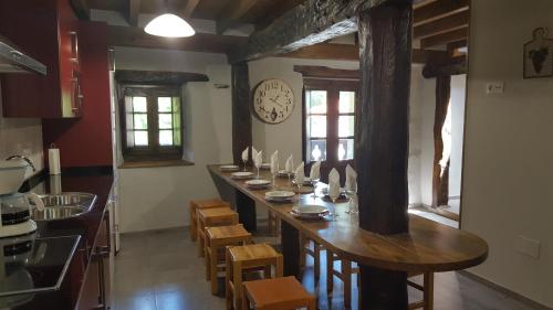 un lungo tavolo in una cucina con un orologio sul muro di Camino de la Torre a Quintana de Soba