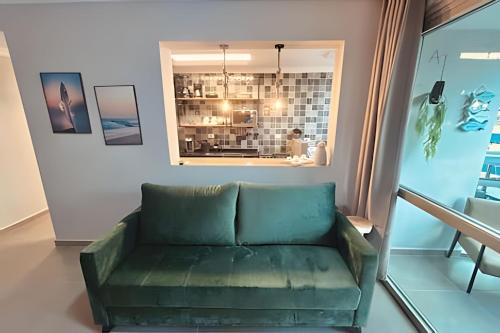 a living room with a green couch and a window at Melhor local de Pitangueiras com serviço de praia in Guarujá