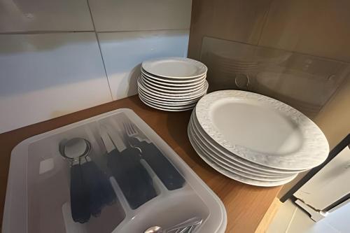 a stack of plates and a sink with a stack of dishes at Melhor local de Pitangueiras com serviço de praia in Guarujá