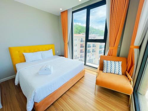 a bedroom with a bed and a chair and a window at We Young Apartments by HOFs - Fireworks & Ocean view in Phú Quốc