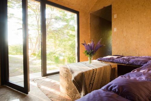 Una habitación con una mesa con un jarrón de flores encima. en Camping Lago Hermoso, en Lago Hermoso