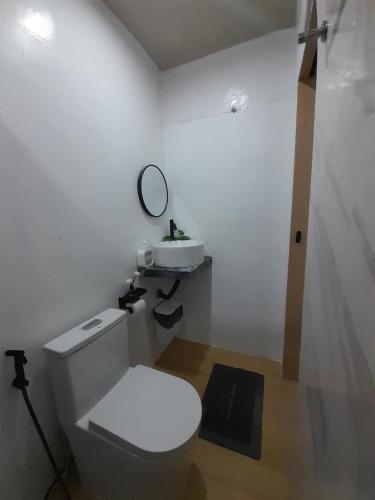 a white bathroom with a toilet and a sink at Happy Island Inn in Virac