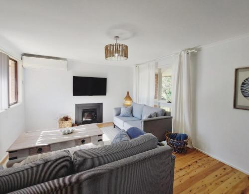 ein Wohnzimmer mit Sofa und Tisch in der Unterkunft Charming Coastal Cottage Retreat in Vincentia