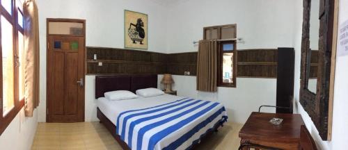 a bedroom with a bed with a blue and white striped blanket at Mini Tiga Homestay in Pangandaran