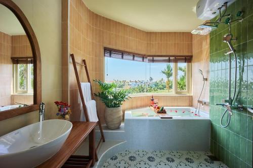 a bathroom with a tub and a sink and a bath tub at LuA House Hoian in Tân Thành (1)