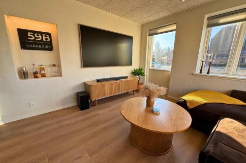 a living room with a flat screen tv and a table at Cozy & Modern Living in Central Odense in Odense