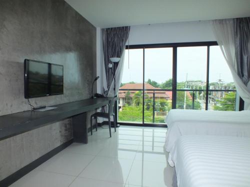 a hotel room with a bed and a tv and window at Hub de Leaf @ Rayong in Rayong