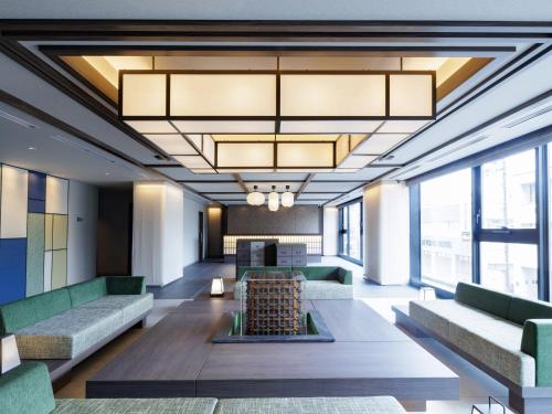 a lobby with couches and tables and windows at HOTEL AMANEK HidaTakayama in Takayama