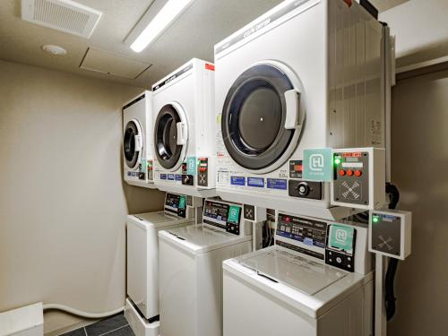 a laundry room with four washers and dryers at HOTEL AMANEK HidaTakayama in Takayama