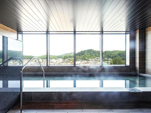 a large swimming pool in a building with a large window at HOTEL AMANEK HidaTakayama in Takayama