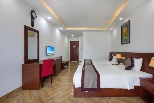 a bedroom with two beds and a desk and a mirror at Gem Nha Trang Hotel in Nha Trang