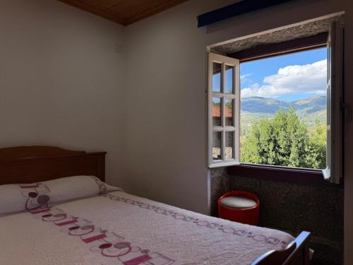 una camera da letto con un letto e una finestra con vista di Casa Veríssimo - Gerês a Terras de Bouro