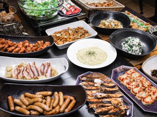 a table filled with different types of food in pans at HOTEL AMANEK HidaTakayama in Takayama