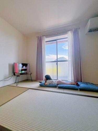 a woman laying on a bed in a room with a window at 飯野小屋 in Marugame