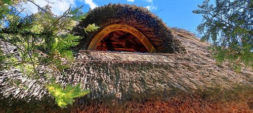 a thatch hut with a window on top of it at Panoráma vendégház in Pécsely