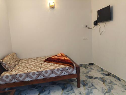 a small bed in a room with a tv on the wall at Nakshatra Homestay in Vattavada