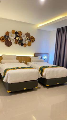 two beds in a room with plates on the wall at Front One The Andia Boyolali in Boyolali
