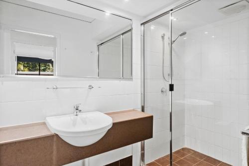 a white bathroom with a sink and a shower at Baden 59 - Rainbow Shores - Pool - Tennis Court - Walk to beach in Rainbow Beach