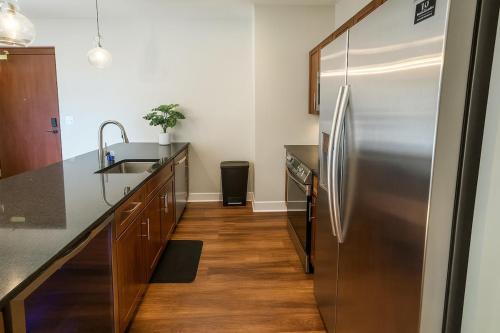 a kitchen with a stainless steel refrigerator and wooden floors at Modern Luxe Airport, Rock Hall, Stadiums, Casino in Cleveland