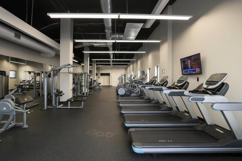 a gym with a row of treadmills and machines at Modern Luxe Airport, Rock Hall, Stadiums, Casino in Cleveland