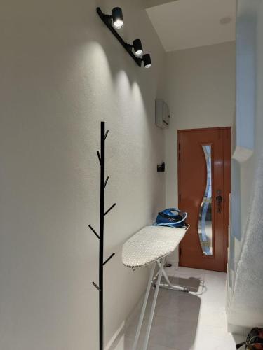 a room with a white wall with a chair and a tree at ZZD Gunong Roomstay in Bachok
