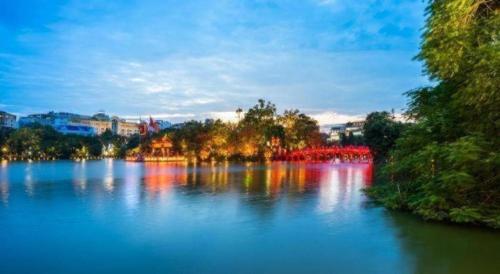 a large lake with trees and buildings in the background at Hoang Hung Hotel in Hanoi