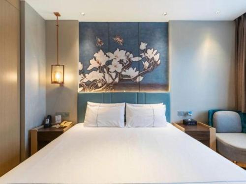 a bedroom with a large white bed with a painting on the wall at Magnotel Business Jining Huancheng North Road in Jining