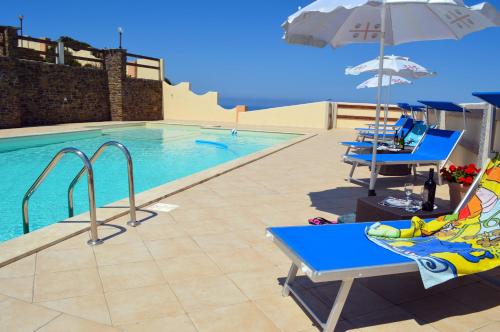 - une piscine avec des chaises bleues et un parasol dans l'établissement Agriturismo Finagliosu, à Palmadula
