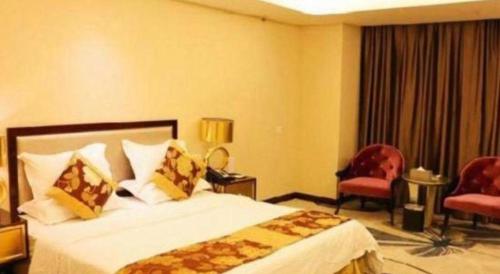 a hotel room with a bed and two chairs at Fuzhou Fuqing Ruixin Hotel in Fuzhou
