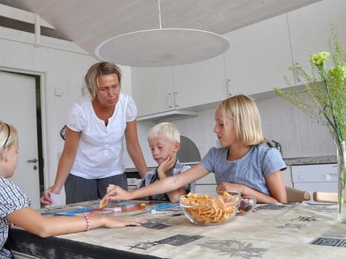 a woman and three children sitting at a table in a kitchen at 6 person holiday home in Skærbæk-By Traum in Skærbæk