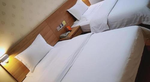 a hotel room with a bed with white sheets and pillows at 7 Days Inn Nanjing Gaochun Metro Station in Gaochun