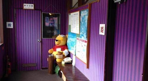 a stuffed winnie the pooh standing in a room at Kakeyu Onsen Hotel Kameya in Ueda
