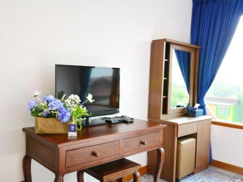 a room with a tv on a dresser with flowers on it at The Indigo House Phrae in Phrae