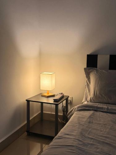 a table with a lamp on it next to a bed at Goldenstay Mutiara Ville Cyberjaya in Cyberjaya