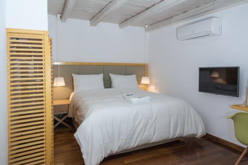a bedroom with a bed and a desk and a tv at Alleyway House in Hydra