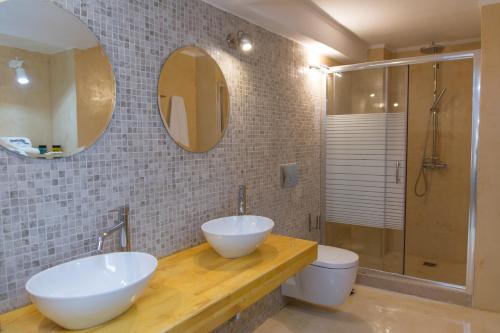 a bathroom with two sinks and a toilet and a mirror at Alleyway House in Hydra