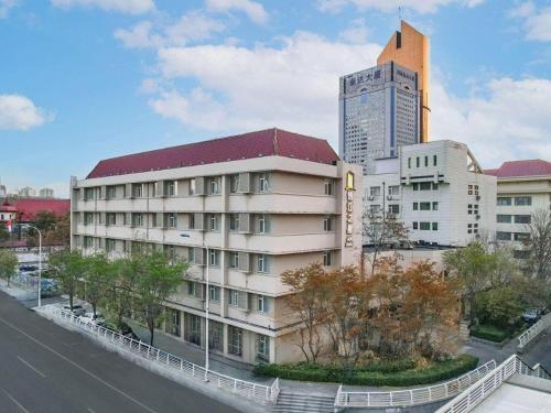 a large building with a tall building in the background at Jinjiang Inn Select Tianjin Xiaobailou Metro Station in Tianjin