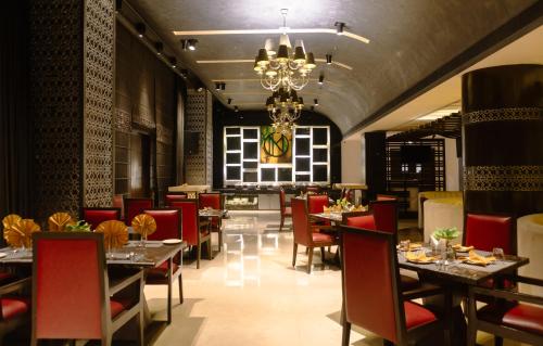 ein Restaurant mit Tischen und Stühlen und einem Kronleuchter in der Unterkunft Udman Hotel Chhattarpur in Neu-Delhi