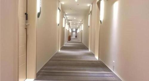 a long corridor with white walls and a long hallway with lights at City Comfort Inn Shenzhen Shiyan Science and Technology Park in Shenzhen