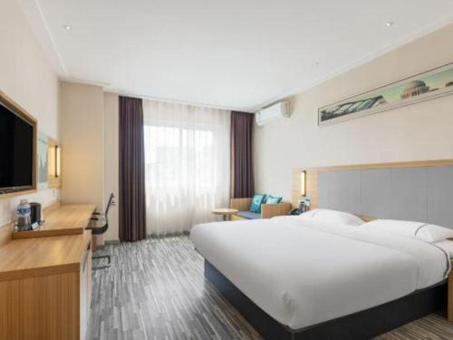 a hotel room with a large bed and a flat screen tv at City Comfort Inn Shantou Daxue Road in Shantou