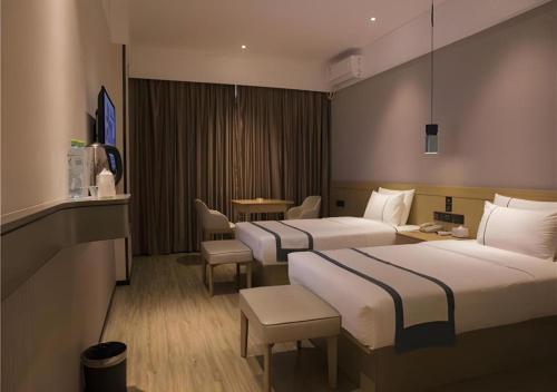 a hotel room with two beds and a table at City Comfort Inn Hainan Tunchang Changsheng Road 