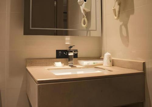 a bathroom counter with a sink and a mirror at City Comfort Inn Hainan Tunchang Changsheng Road 