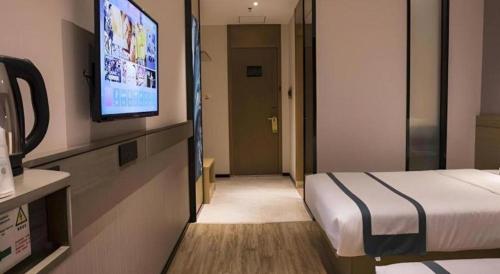 a hotel room with a bed and a flat screen tv at City Comfort Inn Hainan Tunchang Changsheng Road 