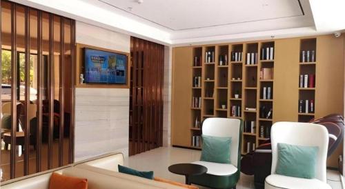 a living room with a couch and chairs and bookshelves at City Comfort Inn Hainan Tunchang Changsheng Road 