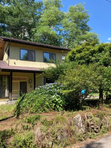 a house with trees and bushes in front of it at 戸隠の小さな民宿,民泊,ゲストハウス神社神社参拝スキーBreath in Earth in Nagano