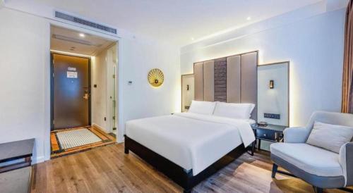a bedroom with a large white bed and a chair at Jinjiang Metropolo Haikou East High Speed Railway Station Normal University in Haikou